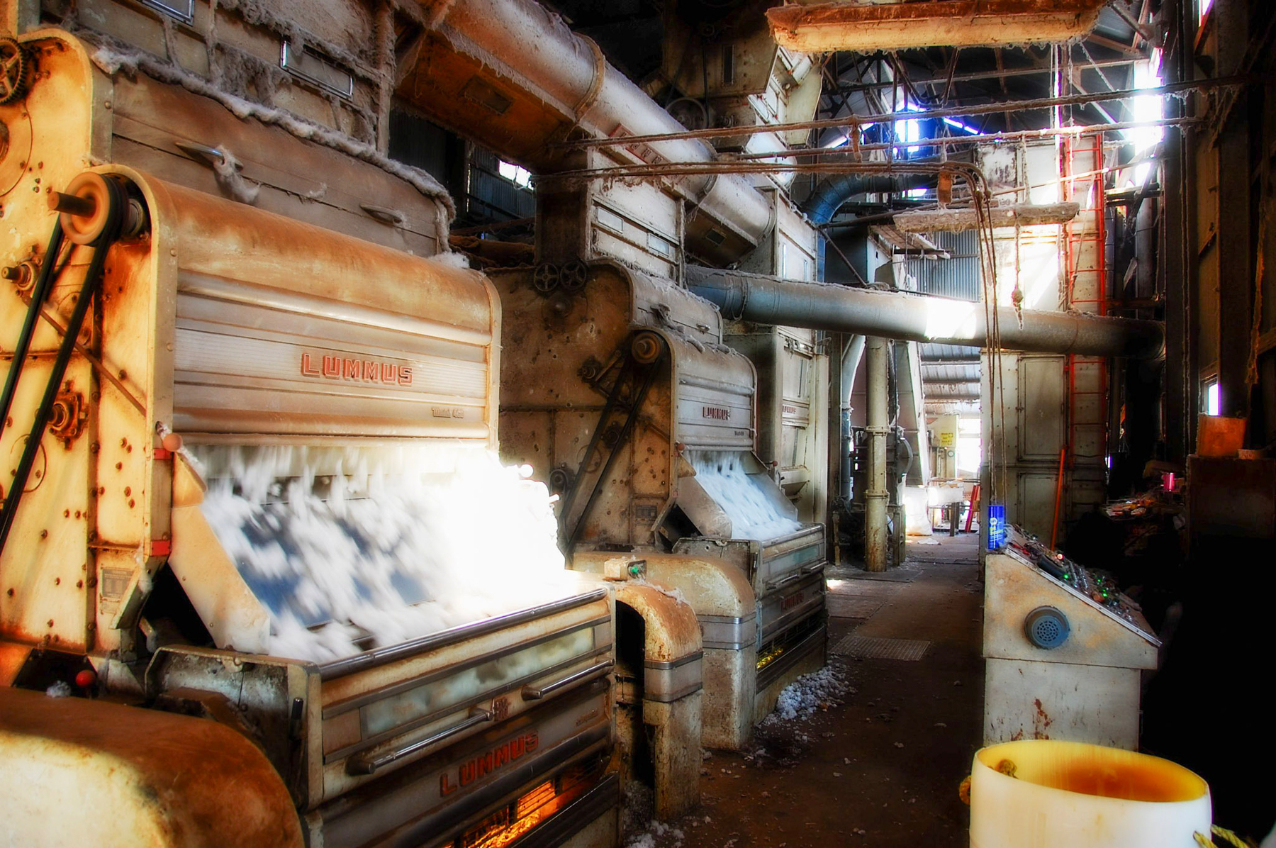 Auto-generated description: An industrial setting with large machinery is engaged in a process involving cotton or a similar material.